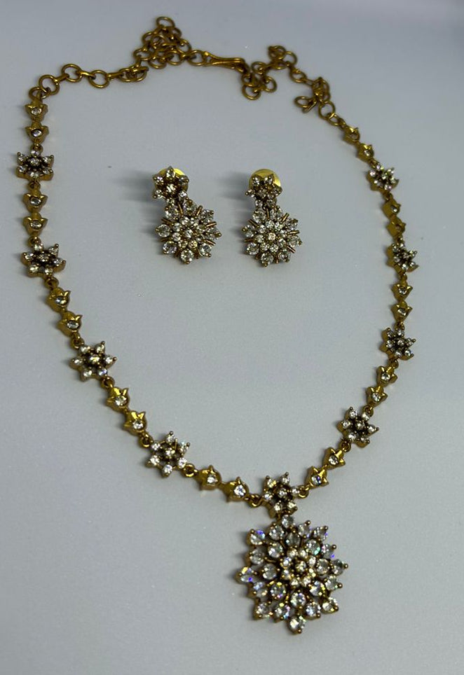 Gold necklace and earrings set on a white background