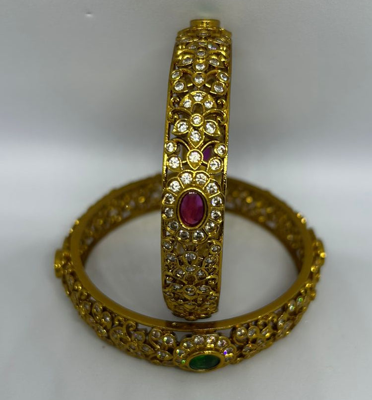 Gold bangles with gemstones on a white background