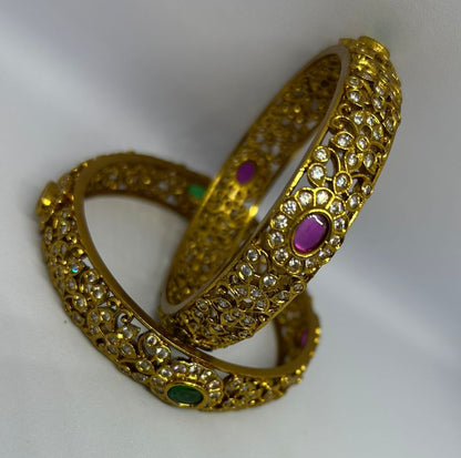 Gold bangles with gemstones on a white background